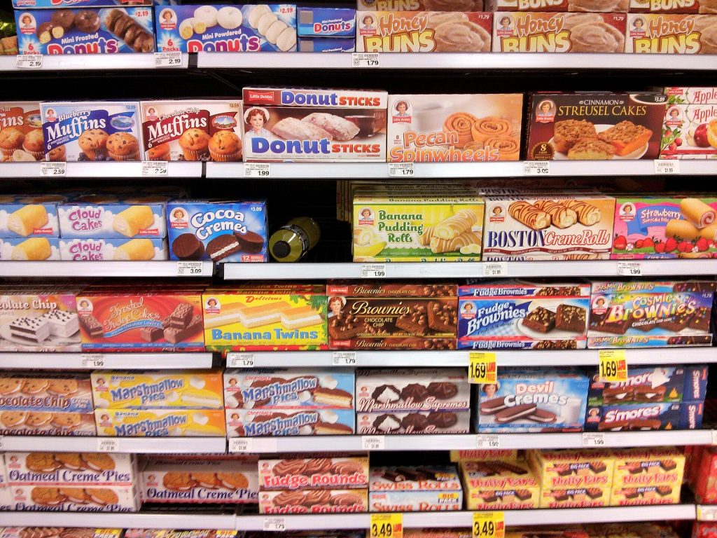 Person reading food labels on packaged products in a supermarket